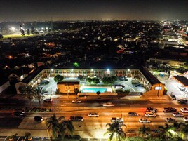 Vista aérea de un hotel con estacionamiento, varios pisos y una piscina.