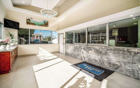 A hotel reception area with a marble counter, a reception desk, and a view of the outside.