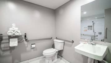 A modern bathroom with a toilet, sink, and handrails.