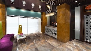 A lobby with a reception desk, a purple chair, and a decorative wall with clocks. - Supreme Hotel (Pune)