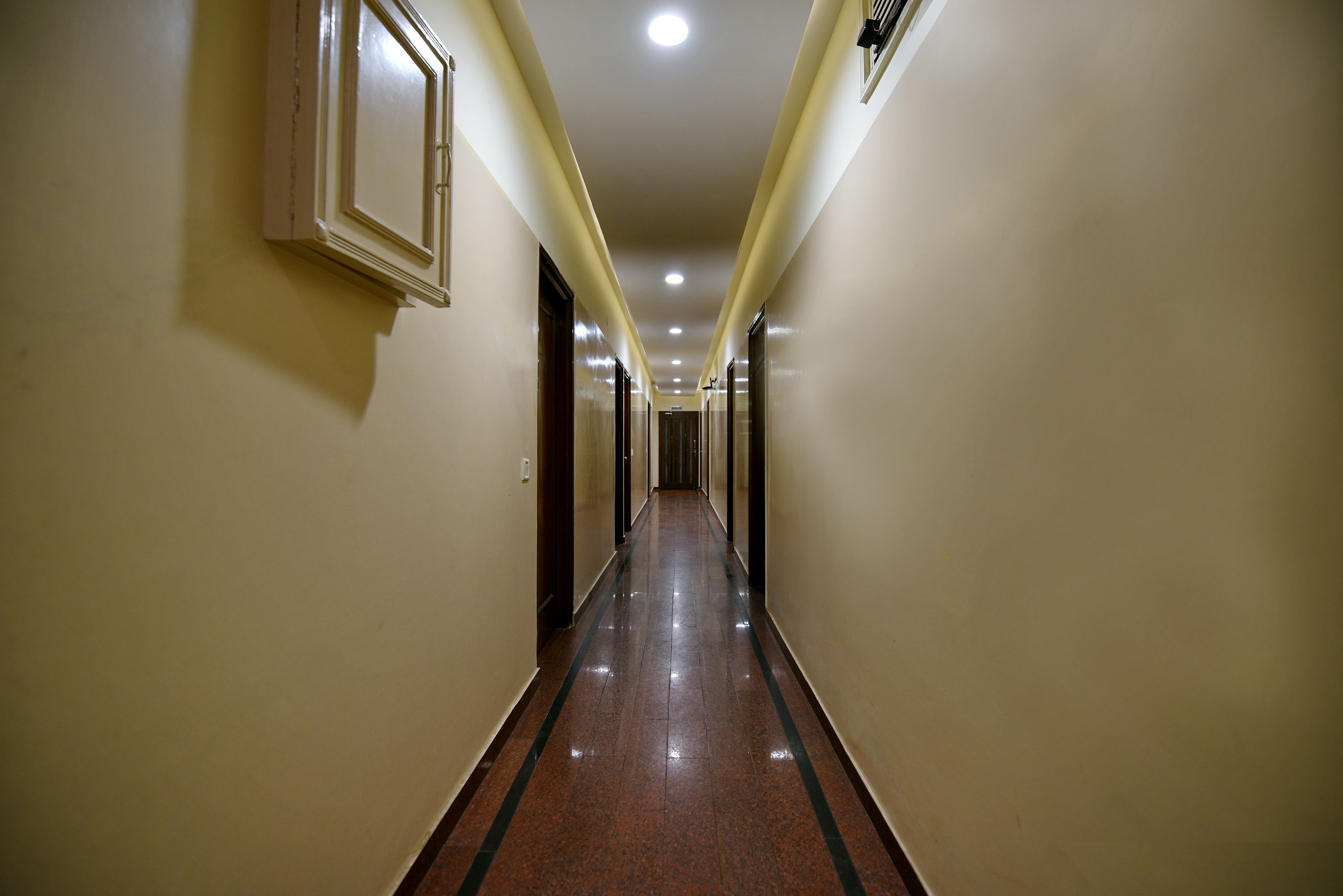 A long, narrow hallway with a shiny, reflective floor and light-colored walls.