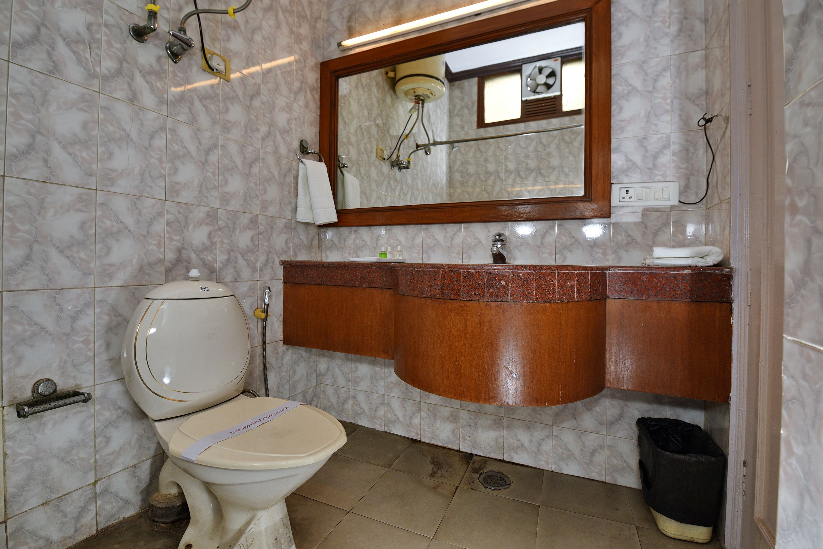 A bathroom with a toilet, sink, mirror, and marble tiles.