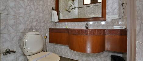 Un baño con inodoro, lavabo, espejo y azulejos de mármol.