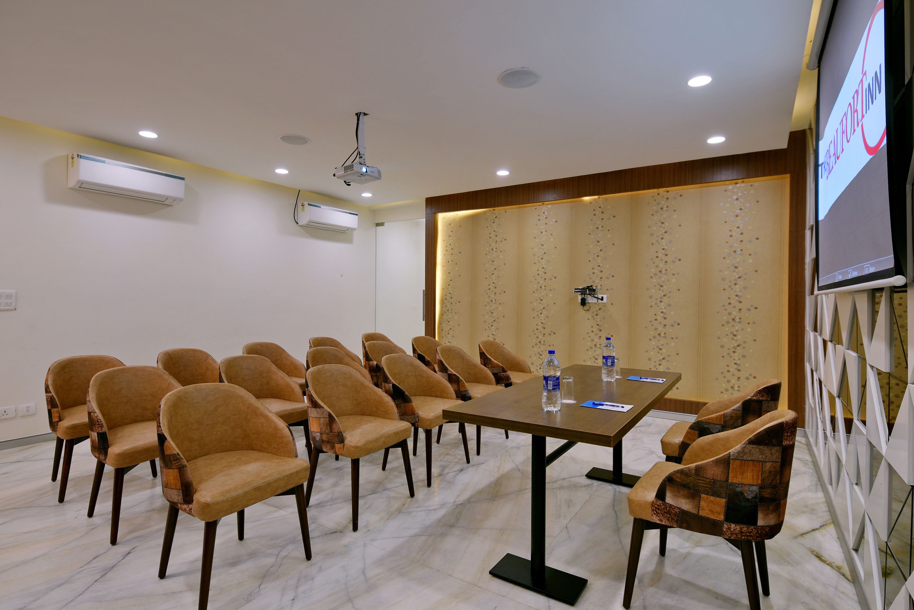A conference room with a long table, multiple chairs, a projector screen, and a water dispenser.