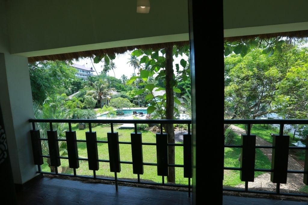 A room with a view of a lush garden and a pool.