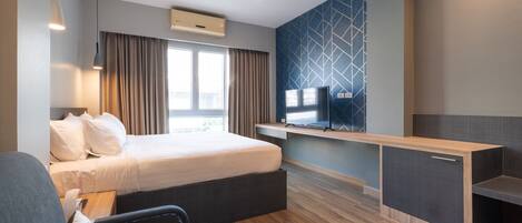Una habitación de hotel moderna con una cama, un escritorio, un televisor y una ventana con cortinas.