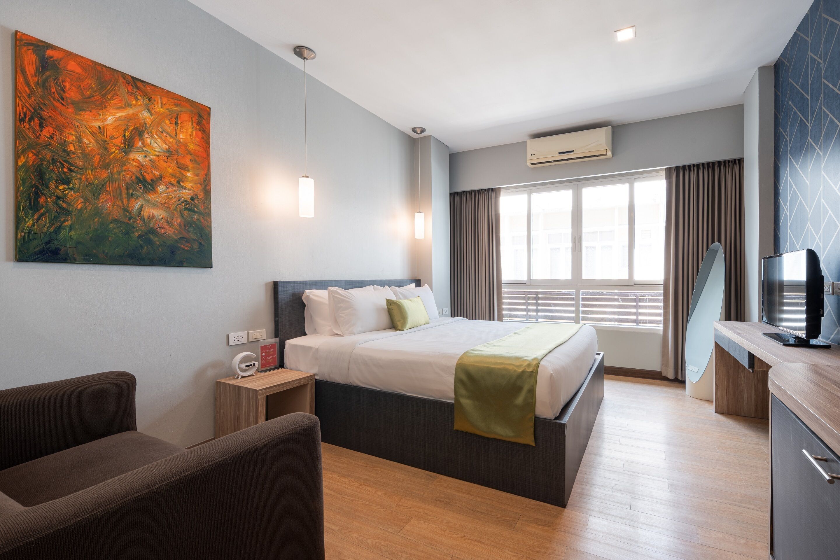 Une chambre d’hôtel moderne, dotée d’un grand lit, d’un bureau, d’une chaise, d’une télévision et d’un tableau au mur.