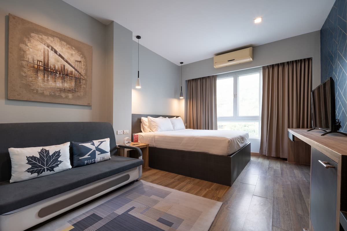 Una habitación de hotel moderna con cama, sofá, escritorio y obras de arte en la pared.