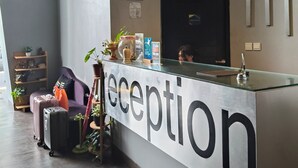 A reception desk with a glass top, a clock, and a sign that reads "reception". - Loft Legian Hotel (Legian)