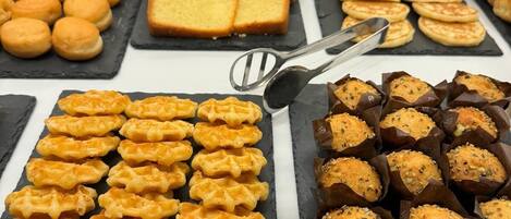 Un bufé con diversas opciones de panadería, incluyendo gofres, bizcochos y pasteles.