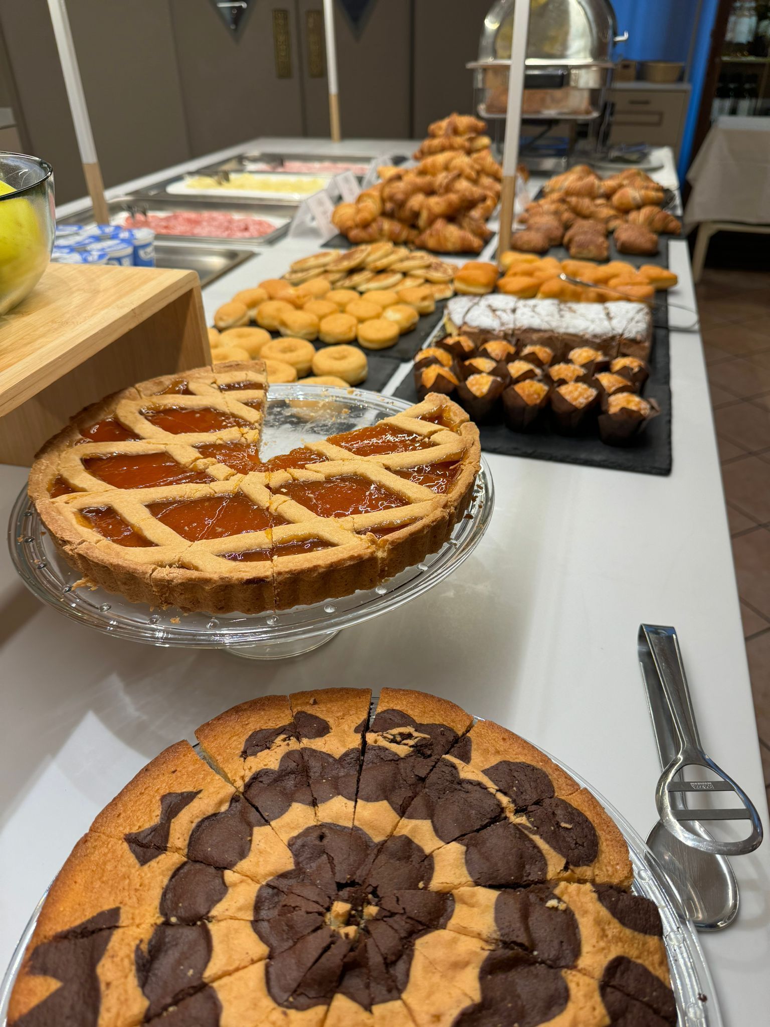 A buffet with various desserts including a cherry pie, chocolate chip cookies, and other pastries.