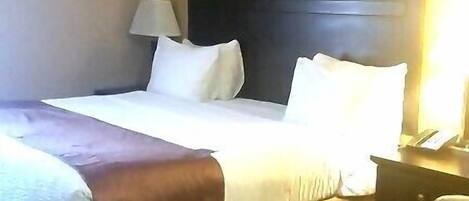 A hotel room with a large bed, a headboard, a bedside table with a lamp, and a chair.