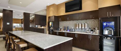 A modern kitchen with a large island, bar stools, and a built-in refrigerator.