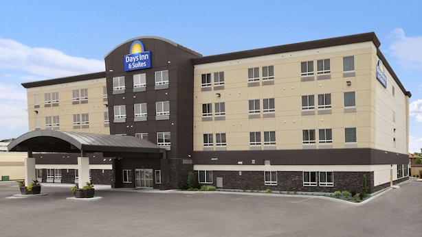 Ein Days Inn Hotel mit modernem Design, inklusive großem Parkplatz und überdachter Einfahrt.