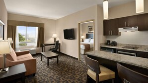 Ein Hotelzimmer mit Küchenzeile, Essbereich, Bett und Fernseher.