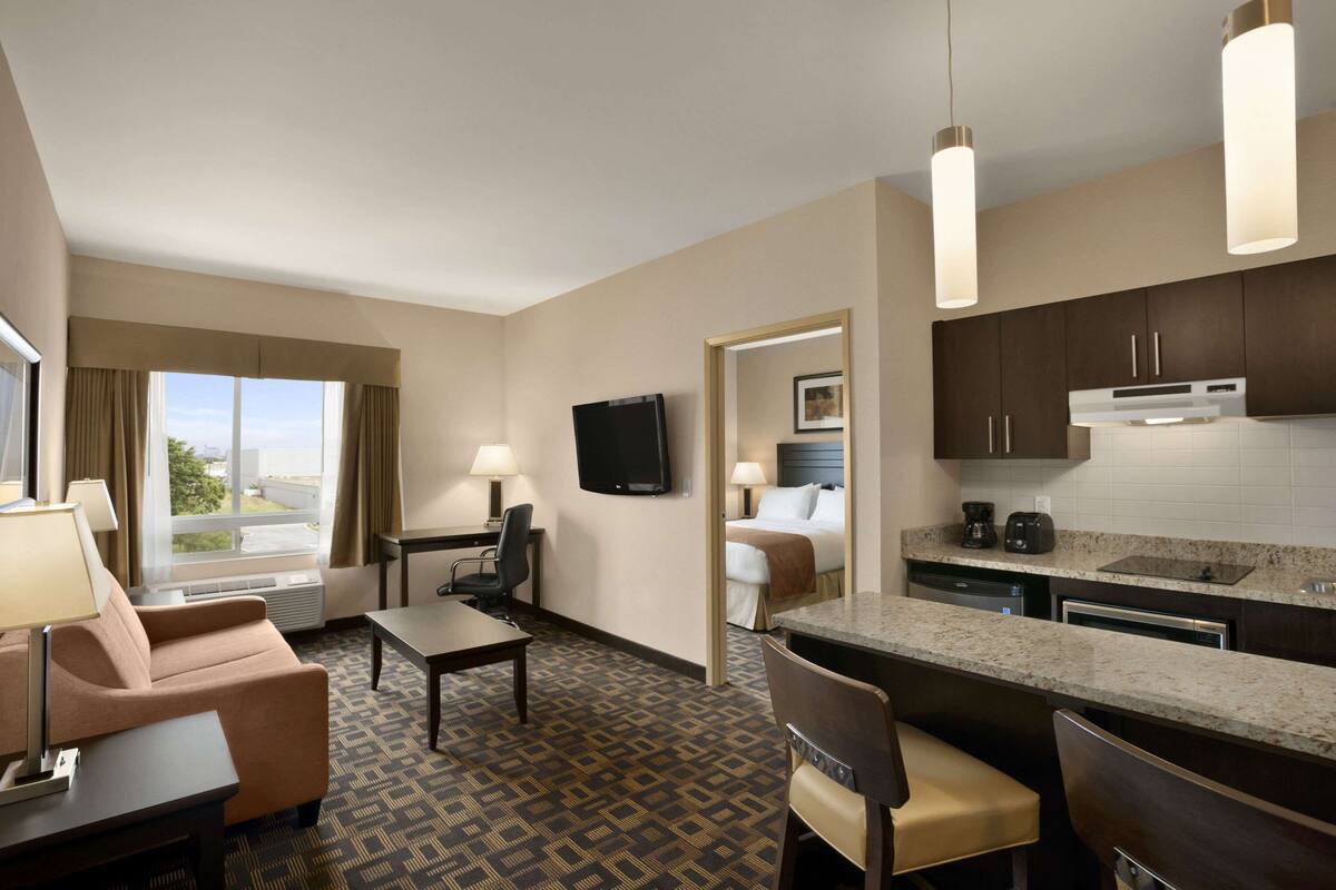 Una habitación de hotel con kitchenette, comedor, cama y televisión.