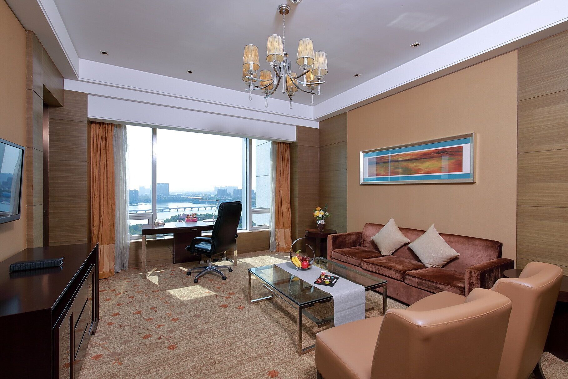 Een moderne hotelkamer met een groot raam, een bureau, een bank en een salontafel.