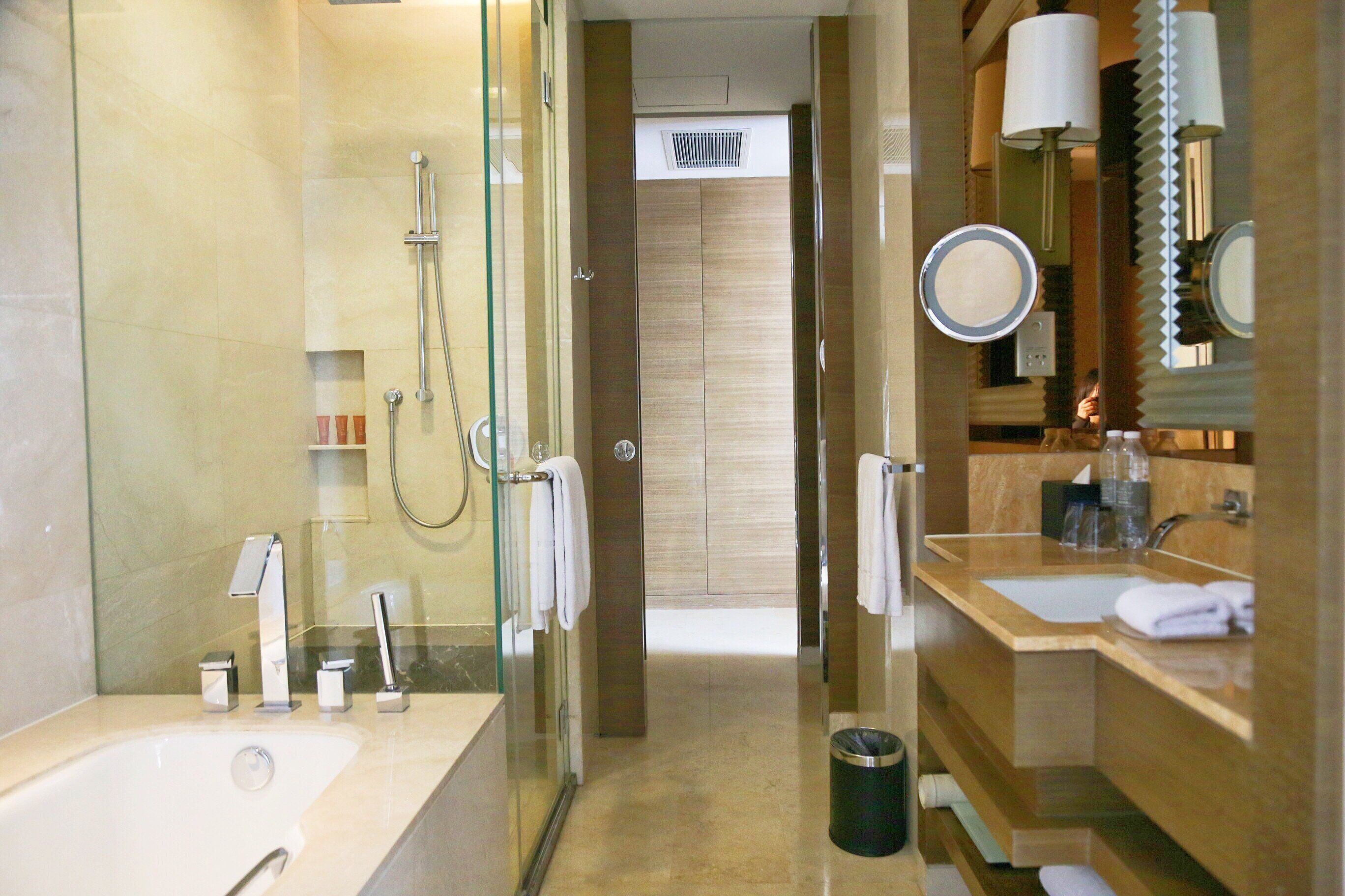 Un baño moderno con ducha envuelta en vidrio, una bañera grande y un tocador con espejo y lavamanos.
