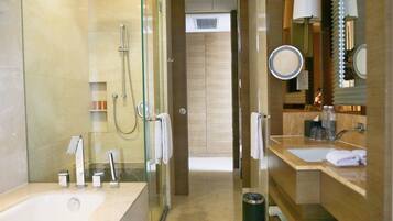 Un baño moderno con ducha envuelta en vidrio, una bañera grande y un tocador con espejo y lavamanos.
