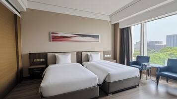 A modern hotel room with two beds, a desk, and a chair.