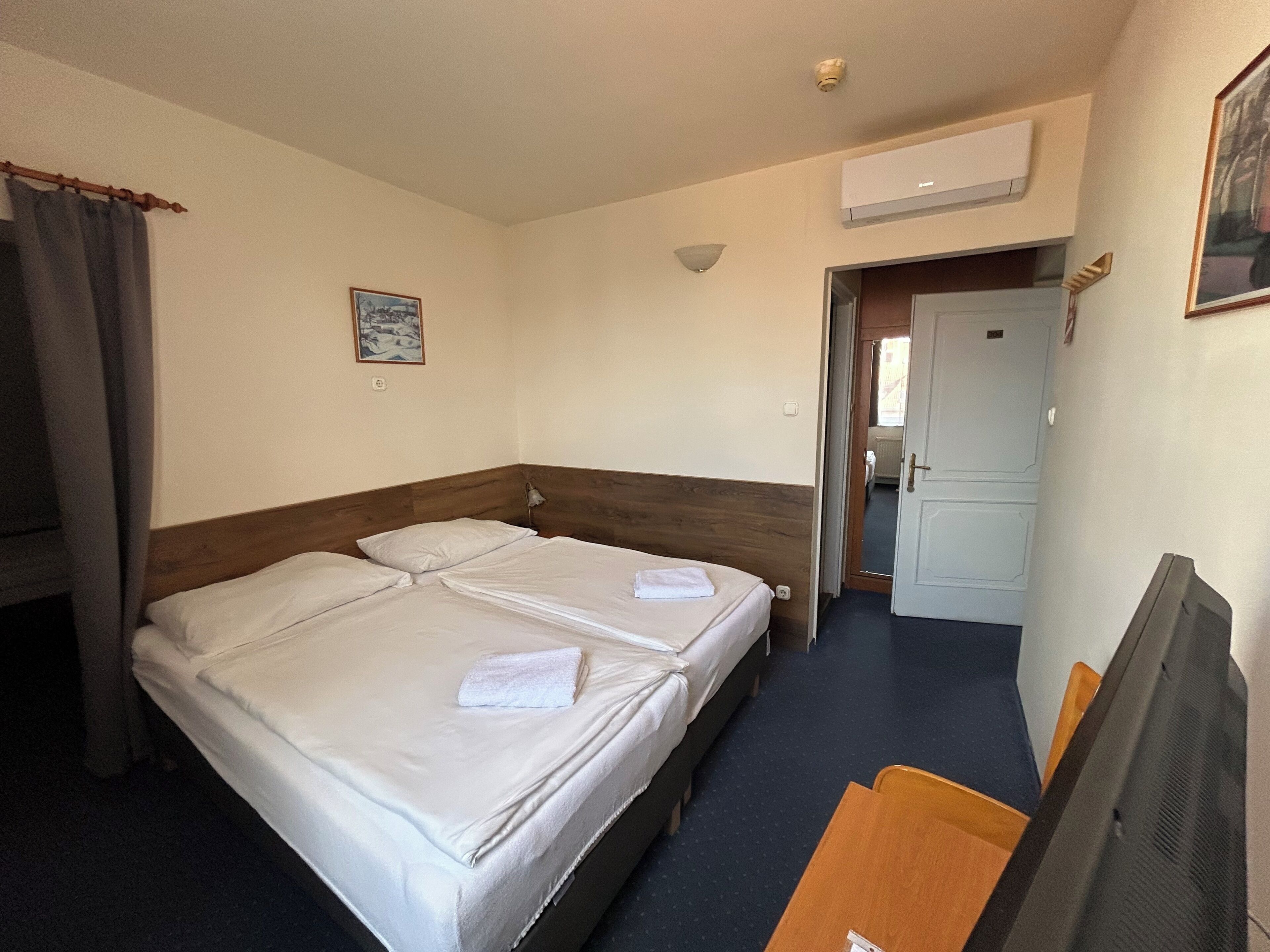 Ein Hotelzimmer mit Doppelbett, Schreibtisch, Stuhl, Fernseher und Klimaanlage.