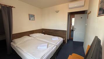 Ein Hotelzimmer mit Doppelbett, Schreibtisch, Stuhl, Fernseher und Klimaanlage.