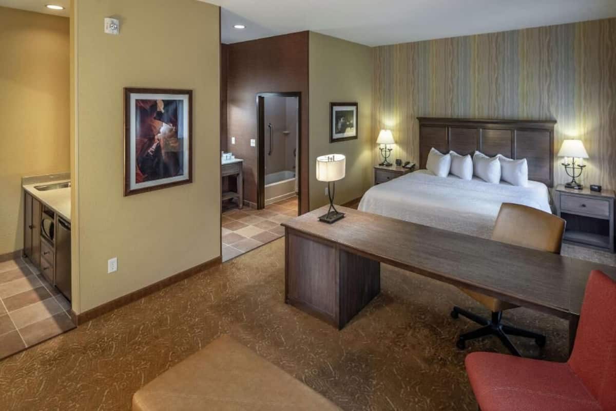 Habitación de hotel con cama, escritorio, silla, ducha y dos lámparas de noche.