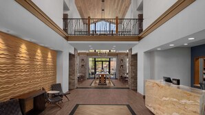A spacious lobby with a herringbone-patterned wall, a reception desk, and a balcony with a railing. - Hampton Inn & Suites Springdale/Zion National Park (Springdale)