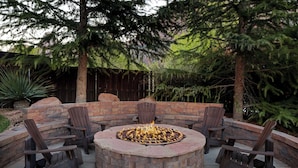 A circular fire pit with seating around it, set in a stone patio area with trees in the background. - Hampton Inn & Suites Springdale/Zion National Park (Springdale)