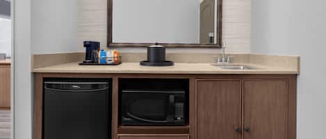 A kitchen with a built-in dishwasher, microwave, and a coffee maker on the countertop.