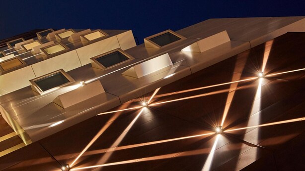 Un edificio moderno con design geometrico e linee illuminate sulla facciata.