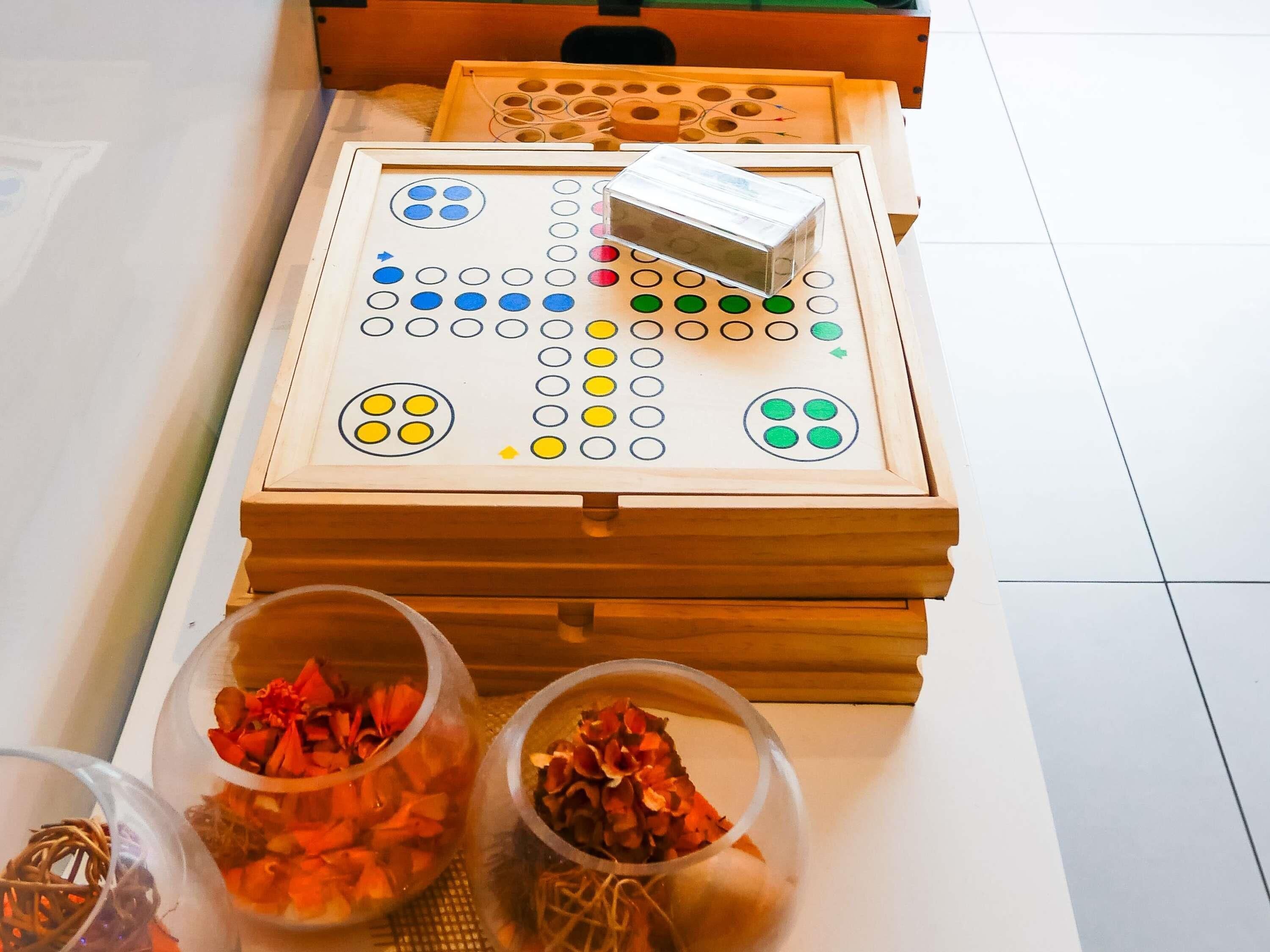 A wooden board game with a box on top, two transparent bowls with dried flowers, and a woven basket.