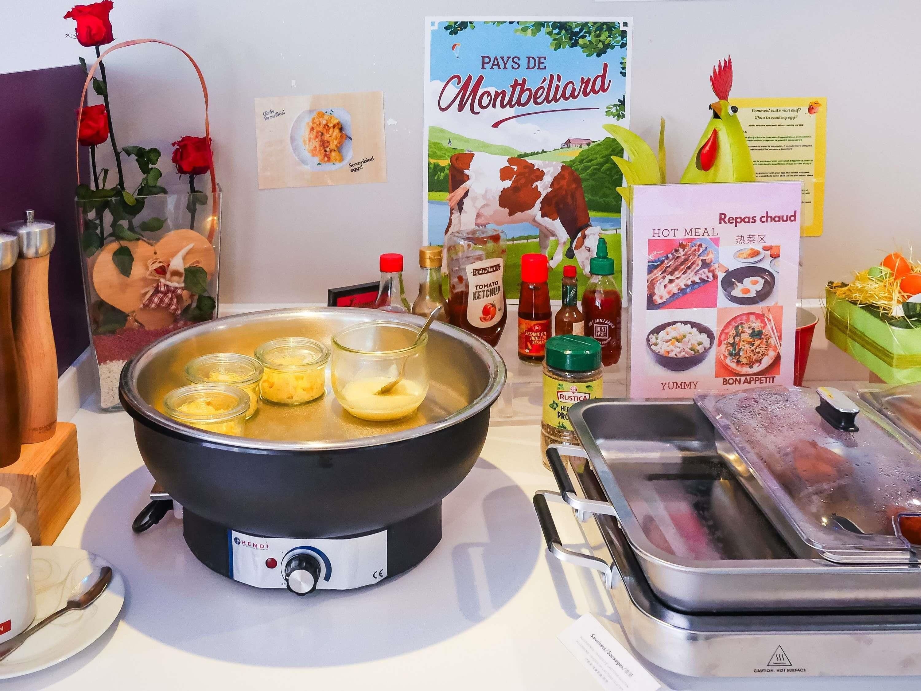 A kitchen with a hot pot, condiments, and a poster of Montbéliard.