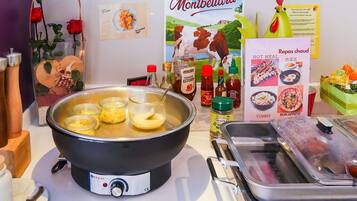 A kitchen with a hot pot, condiments, and a poster of Montbéliard.