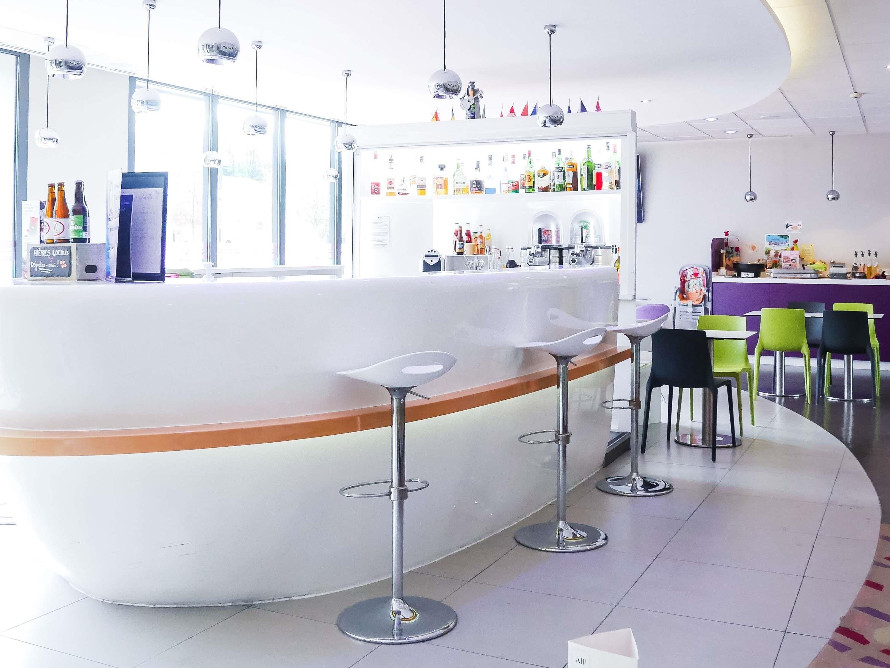 Un área de bar moderna con una barra curva, taburetes y una variedad de bebidas.