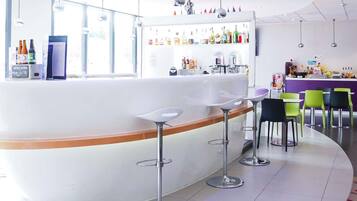 Un área de bar moderna con una barra curva, taburetes y una variedad de bebidas.