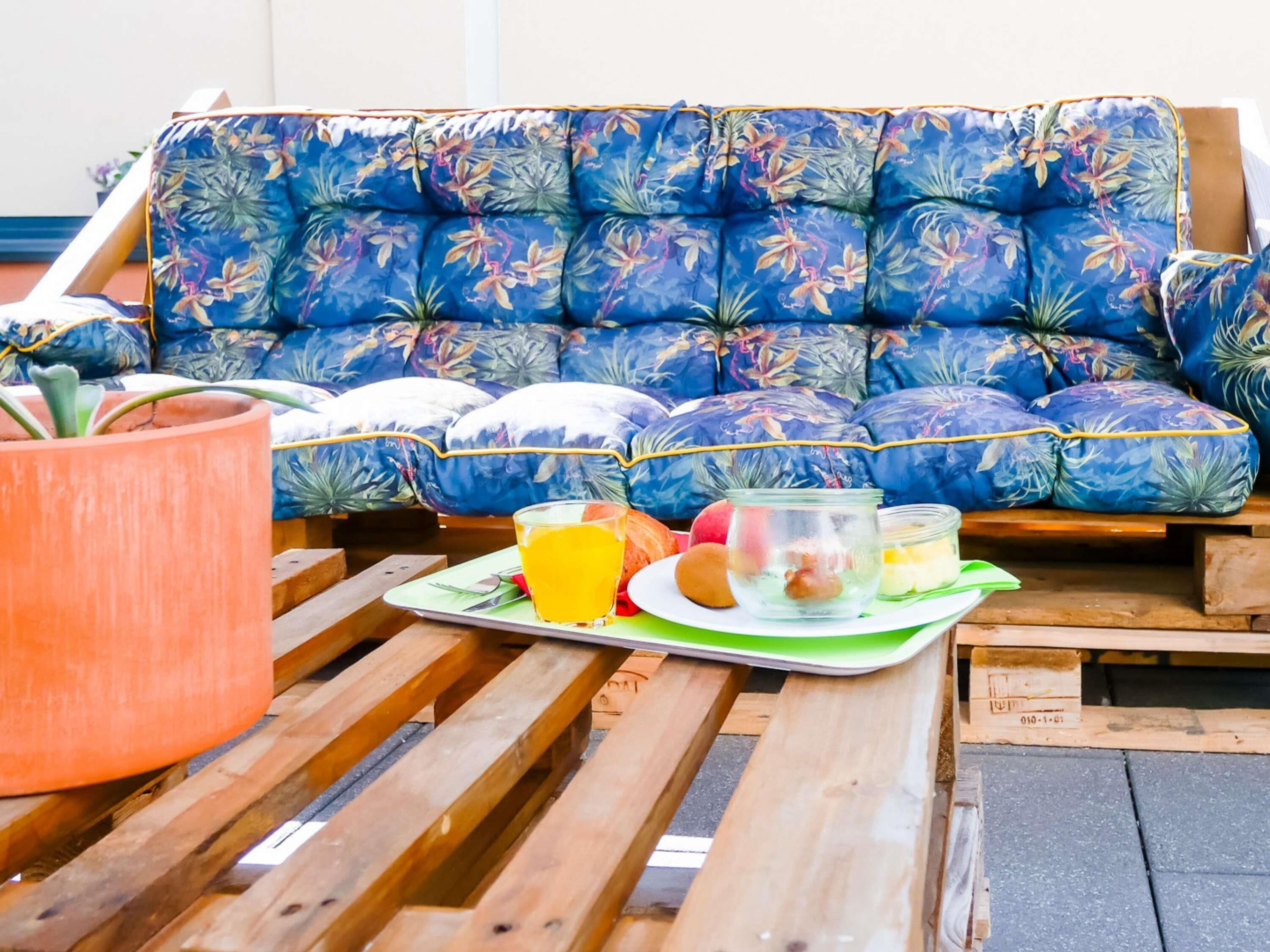 A blue floral sofa with a tray of food and drinks on a wooden table.