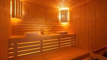Un sauna en bois, avec des bancs, un seau et des serviettes.