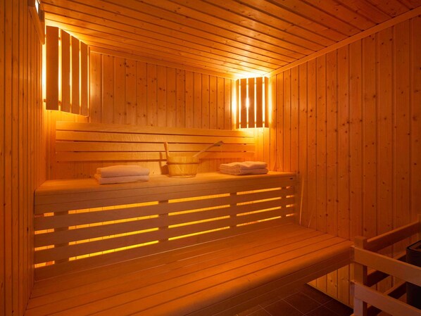 A wooden sauna with benches, a bucket, and towels.