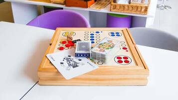 Un jeu de société en bois comprenant des dés, des cartes à jouer et un baby-foot, le tout posé sur une table.