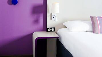Une chambre d’hôtel équipée d’un lit, d’une table de chevet, d’une lampe et d’une prise électrique.