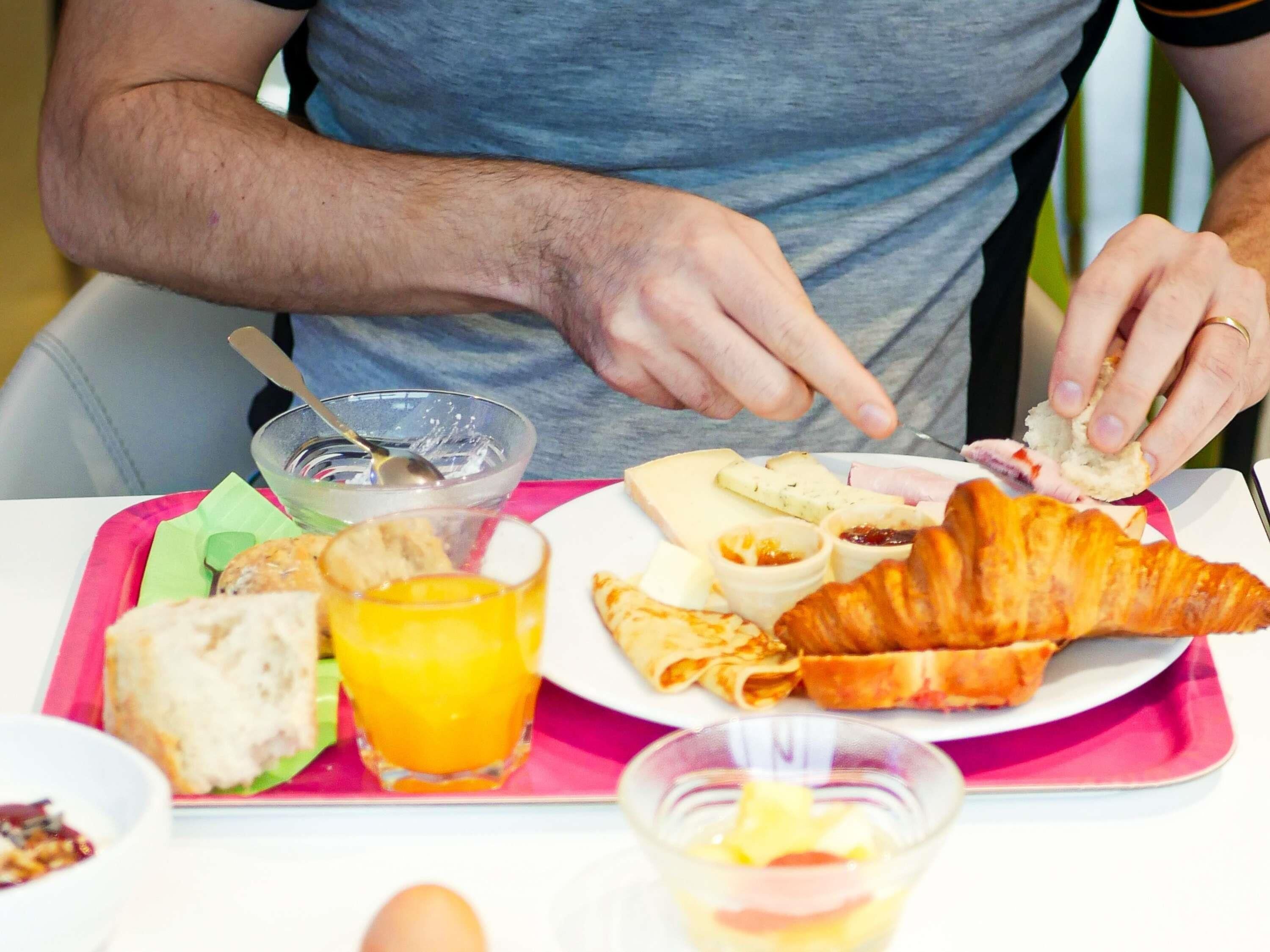 A breakfast tray with bread, croissants, cheese, and a glass of orange juice.