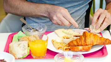 A breakfast tray with bread, croissants, cheese, and a glass of orange juice.