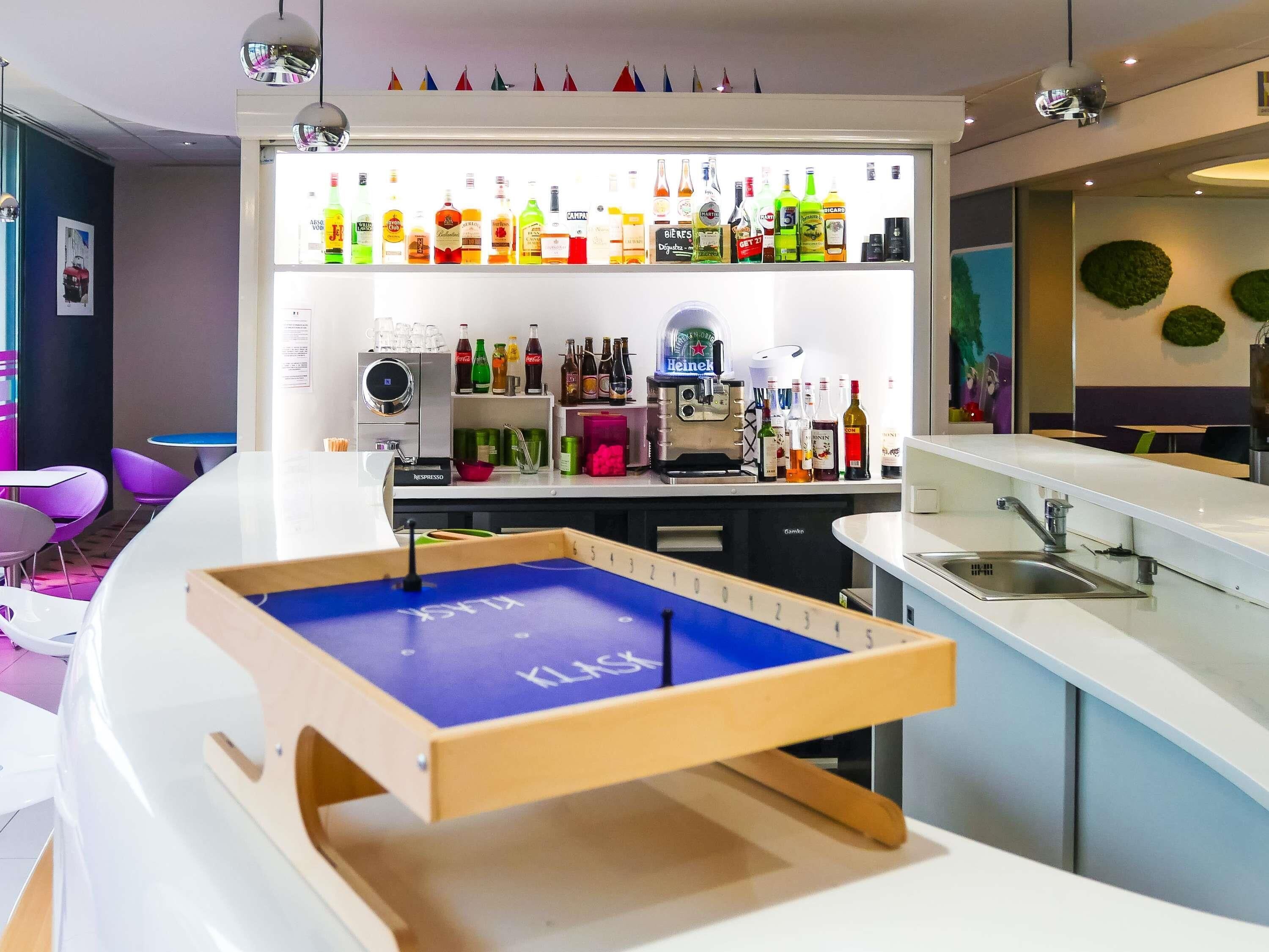 Un bar moderno con una variedad de botellas de licor, una máquina de café y una mesa de billar.