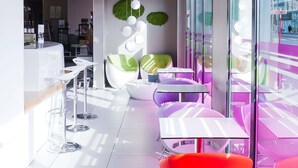 Un interior moderno con muebles blancos y morados, una zona de bar y vistas amplias a través de grandes ventanales.