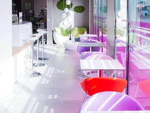 Ein modernes Interieur mit weißer und violetter Möbel, einer Bar und Blick durch große Fenster.