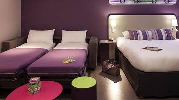A hotel room with two beds, a small table, a chair, a nightstand, and a wall-mounted artwork.