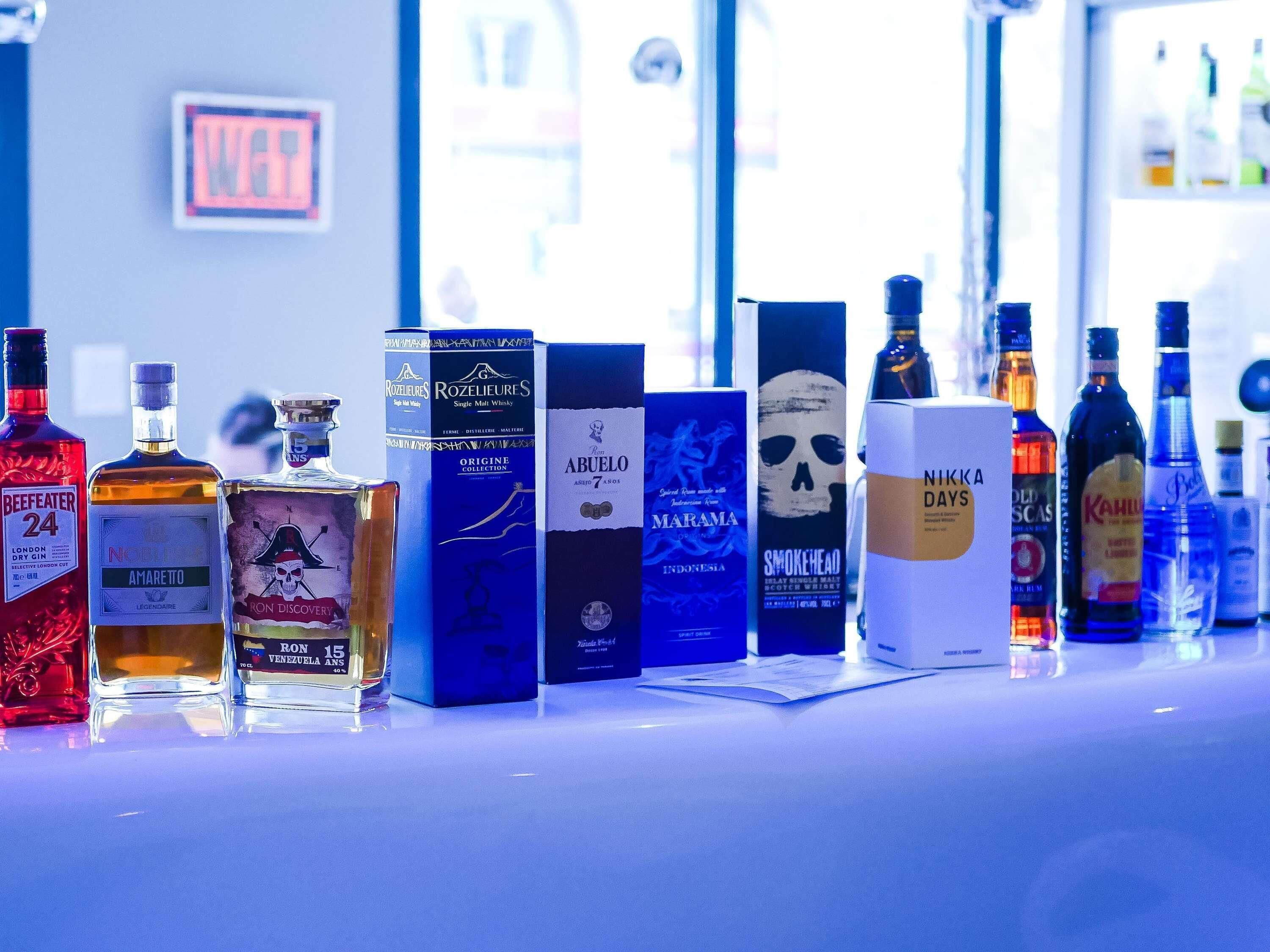 Variedad de botellas y cajas de licores sobre una barra.