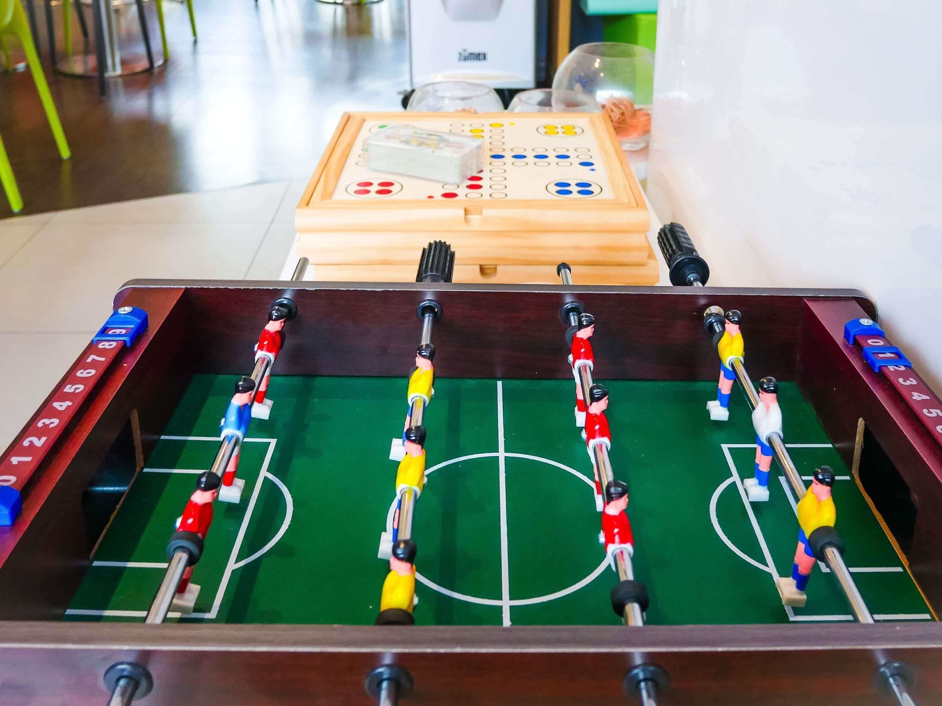 Ein Kicker mit Holzrahmen, einer grünen Spielfläche und zwei Mannschaften Spieler.