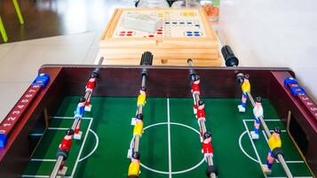 Ein Kicker mit Holzrahmen, einer grünen Spielfläche und zwei Mannschaften Spieler.